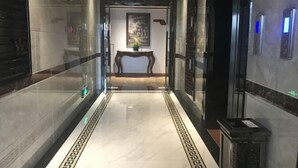 A modern hallway with a marble floor, a wooden bench, and a painting on the wall. - Wangxinge Hotel (Nan County)