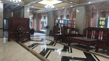 A lobby with a large chandelier, a reception desk, and a seating area with a patterned floor.