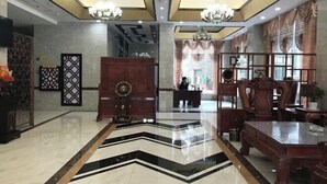 A lobby with a modern design, featuring a geometric patterned floor, a reception desk, and a chandelier. - Wangxinge Hotel (Nan County)