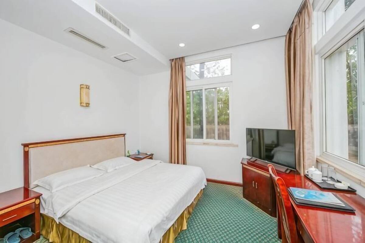 Een hotelkamer met een bed, een televisie, een bureau en een raam.