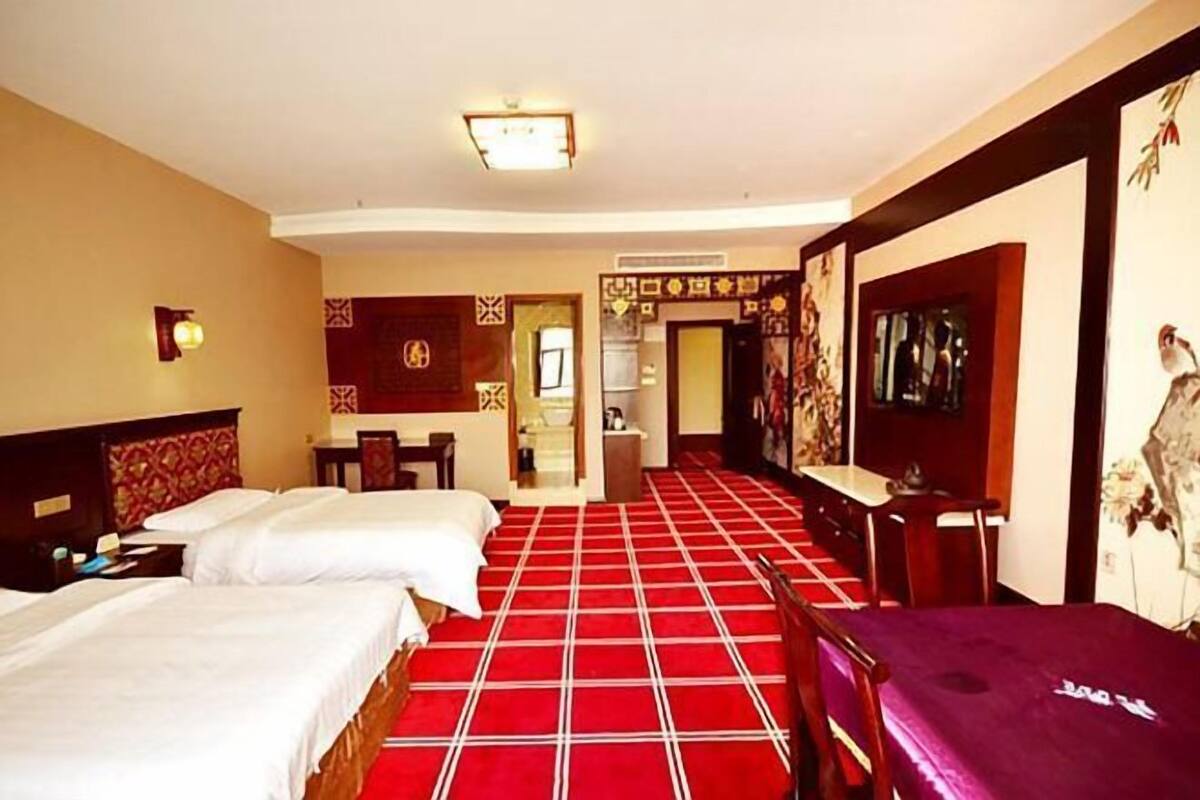 Een hotelkamer met twee bedden, een vloer met een rood geruit patroon, een bureau en een spiegel.