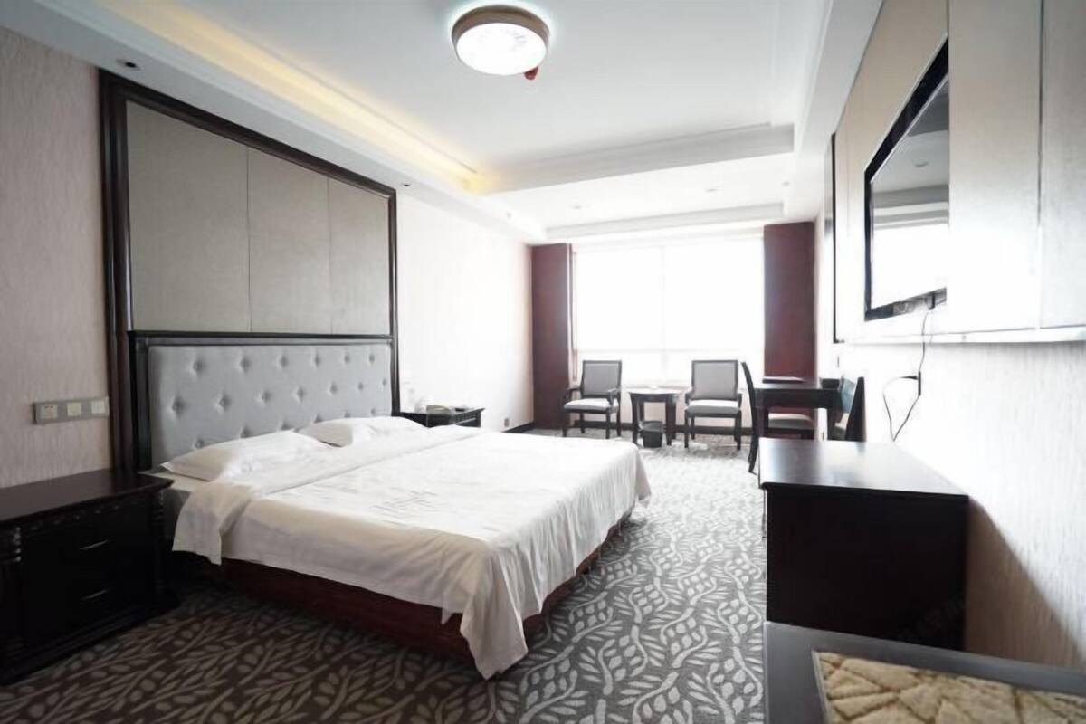 Een hotelkamer met een groot bed, een bureau, een stoel en een televisie.