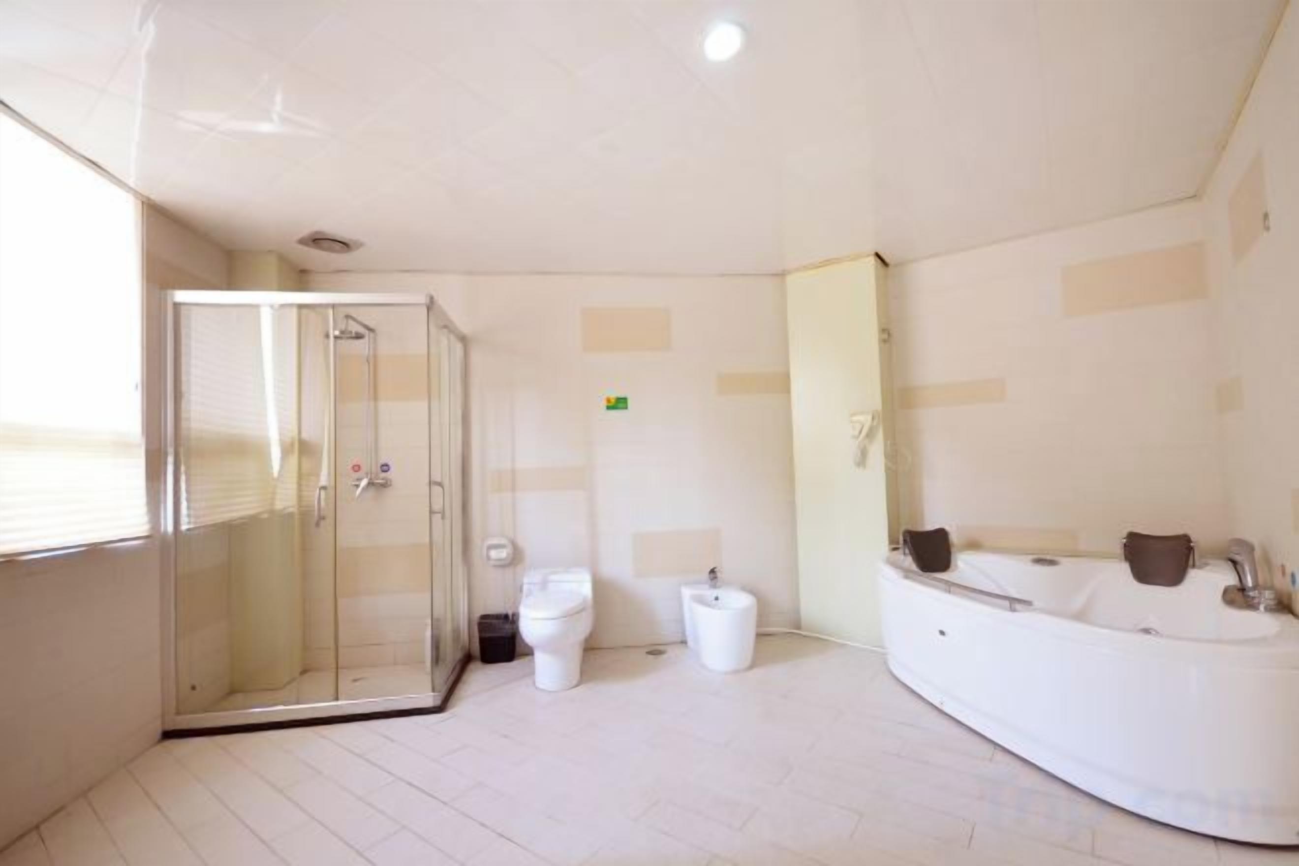Un baño con cabina de ducha de vidrio, bañera y dos inodoros.
