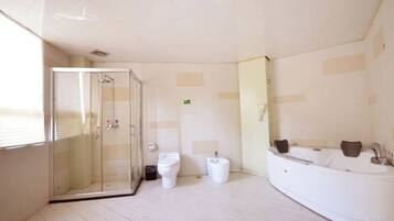 Un baño con cabina de ducha de vidrio, bañera y dos inodoros.