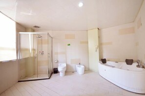 Un baño con cabina de ducha de vidrio, bañera y dos inodoros.