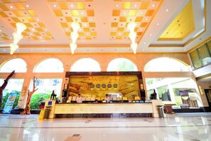 Un hall espacioso con mostrador de recepción, amplias ventanas de arco y un techo decorativo.