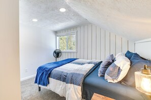 Een slaapkamer met een bed, een ventilator, een raam en een plafondventilator.