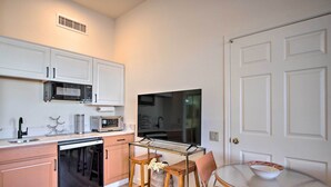 Una cocina compacta equipada con lavavajillas, microondas y una pequeña mesa de comedor con sillas.