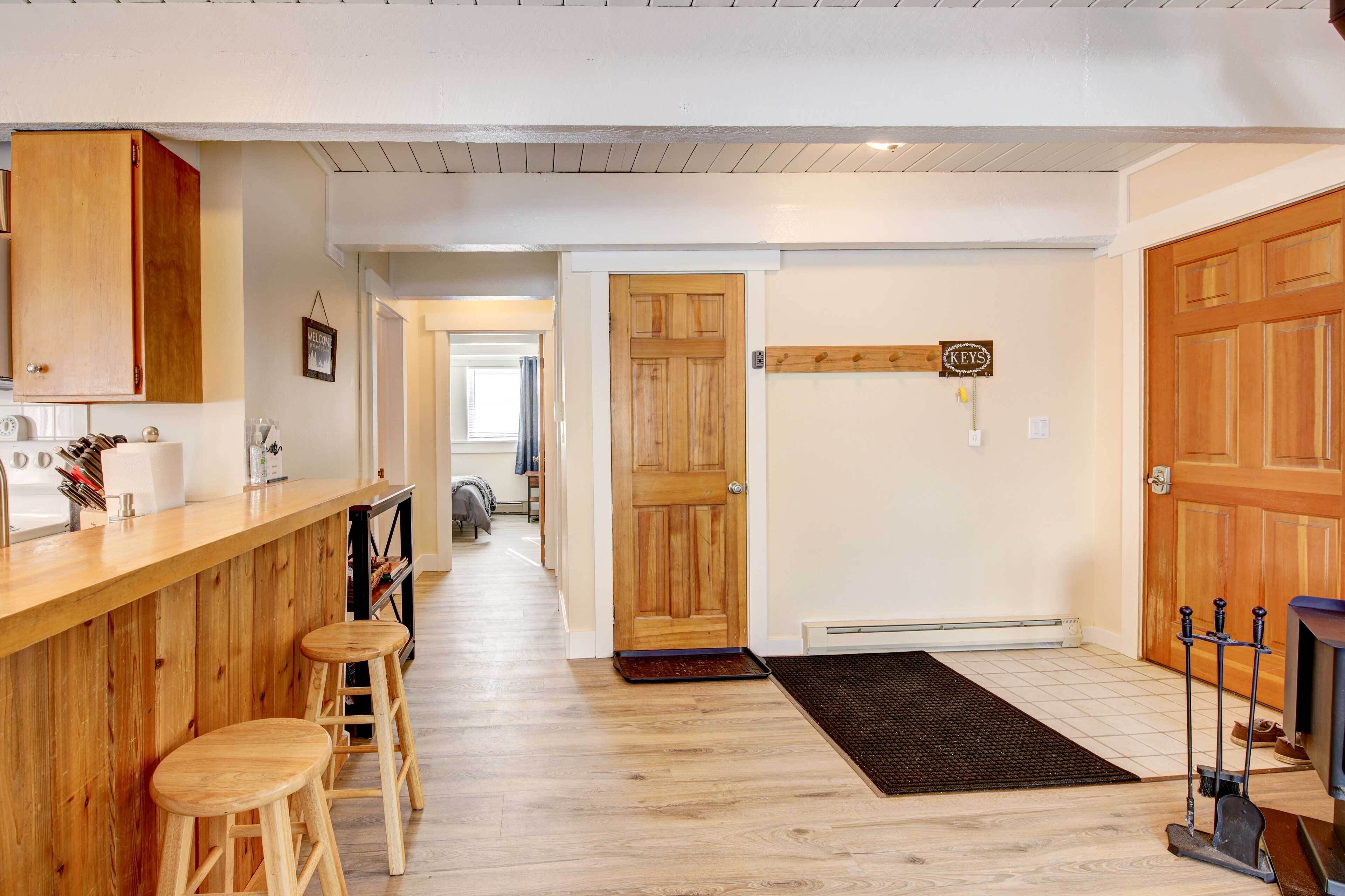 Una cocina con armarios de madera, una barra con taburetes y una puerta con el letrero 'KEYS'.