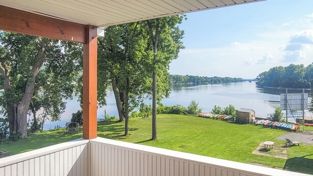 Un balcon avec vue sur une rivière et une zone herbeuse équipée d’aires de jeux pour enfants.