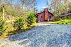Ein rustikales Blockhaus mit Kiesweg, umgeben von Bäumen und einem kleinen Garten.
