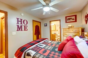 Ein Schlafzimmer mit einem Bett, einem Deckenventilator, einer Holzkommode und einer Wand mit dem Wort 'HOME' und einem Bärenbild.