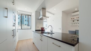 Uma cozinha moderna com armários brancos, bancada preta e janela com vista para a cidade.