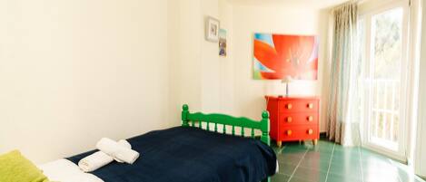 A bedroom with a bed, a dresser, a painting, and a window.