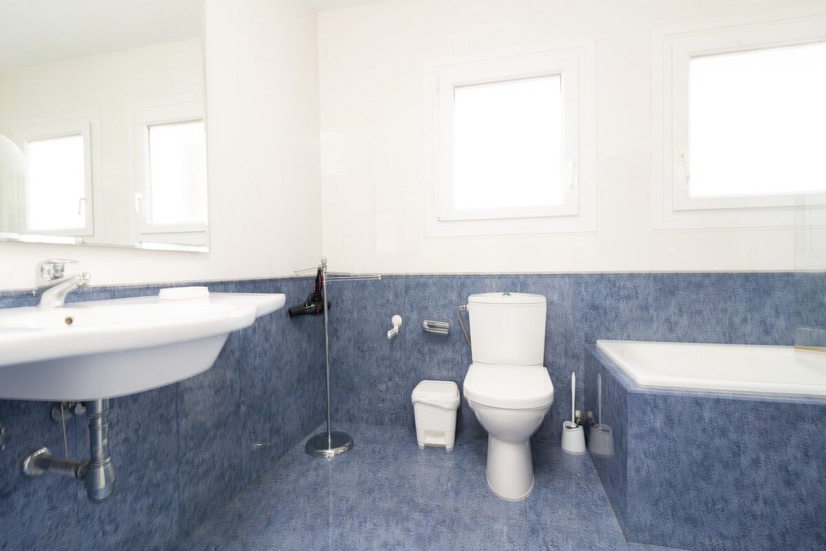 A bathroom with a white sink, toilet, and bathtub, and blue-tiled walls.
