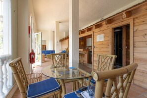 Una cabaña de madera con una mesa y sillas de vidrio, un extintor y una puerta visible.