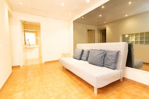 Una habitación con un sofá, una mesita y una ventana.