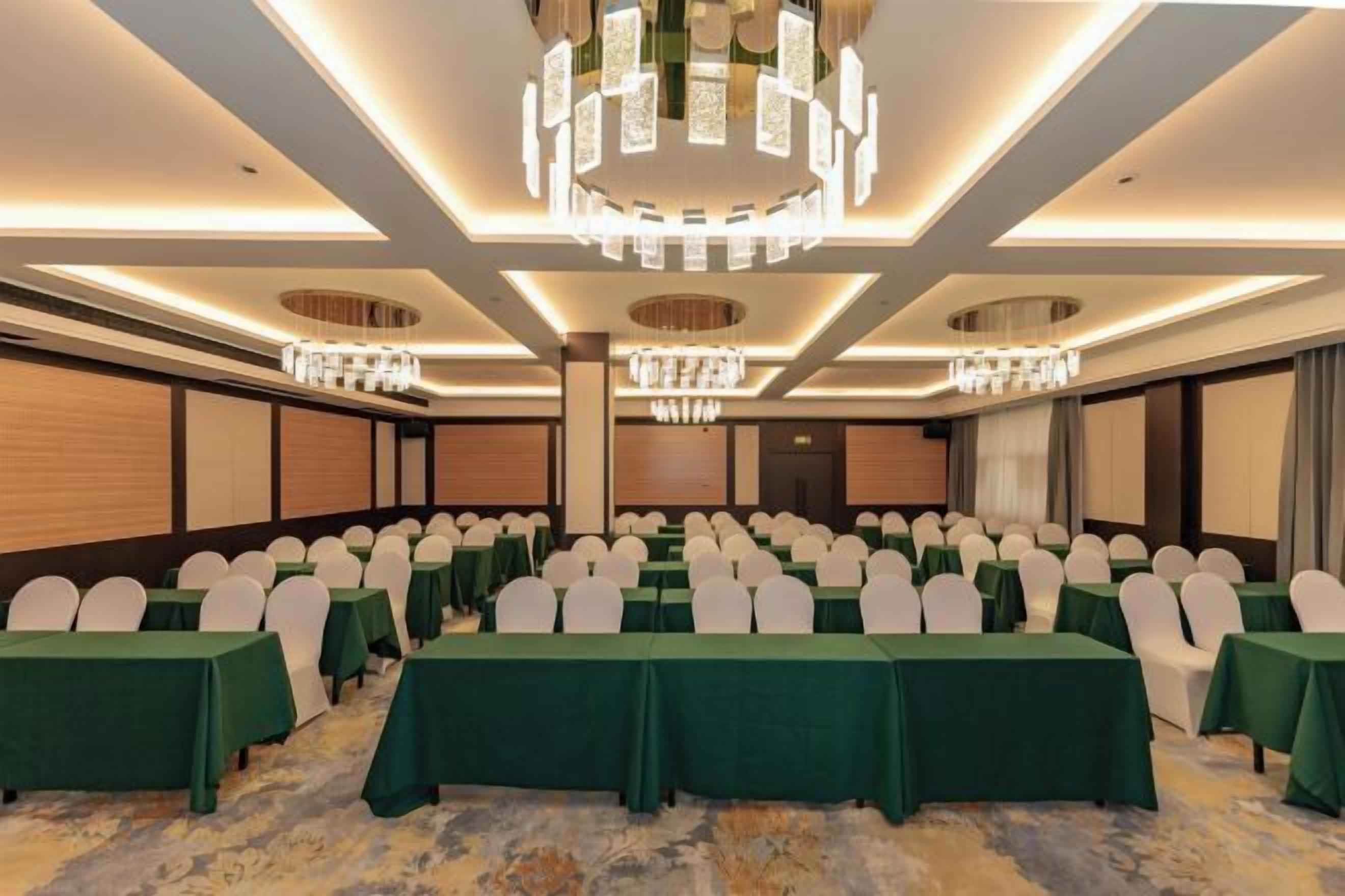 A conference room with rows of tables, chairs, and a chandelier.
