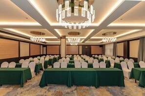 Un salón de conferencias con mesas, sillas y una araña.
