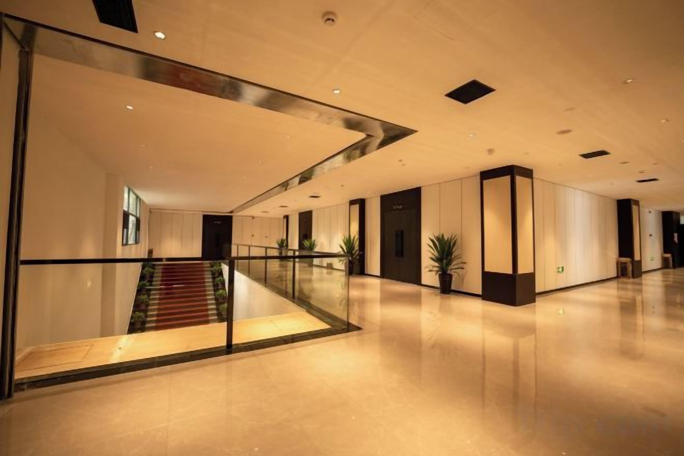 A spacious hotel lobby with a glass railing, a staircase, and a polished floor.