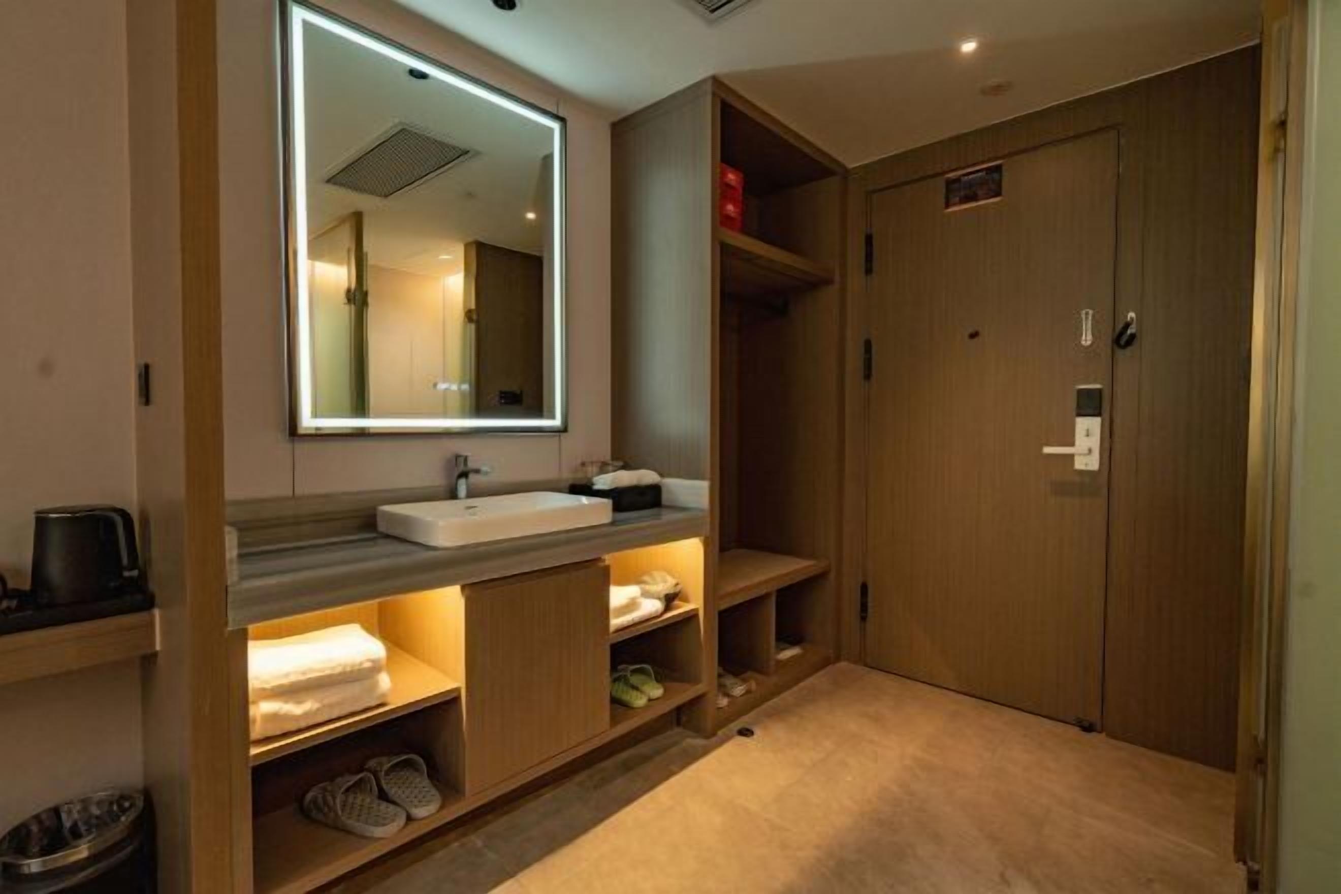 Un baño moderno con un espejo grande, tocador de madera y estantes empotrados.