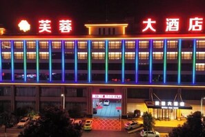 A hotel with a modern facade, multiple floors, and a brightly lit entrance.