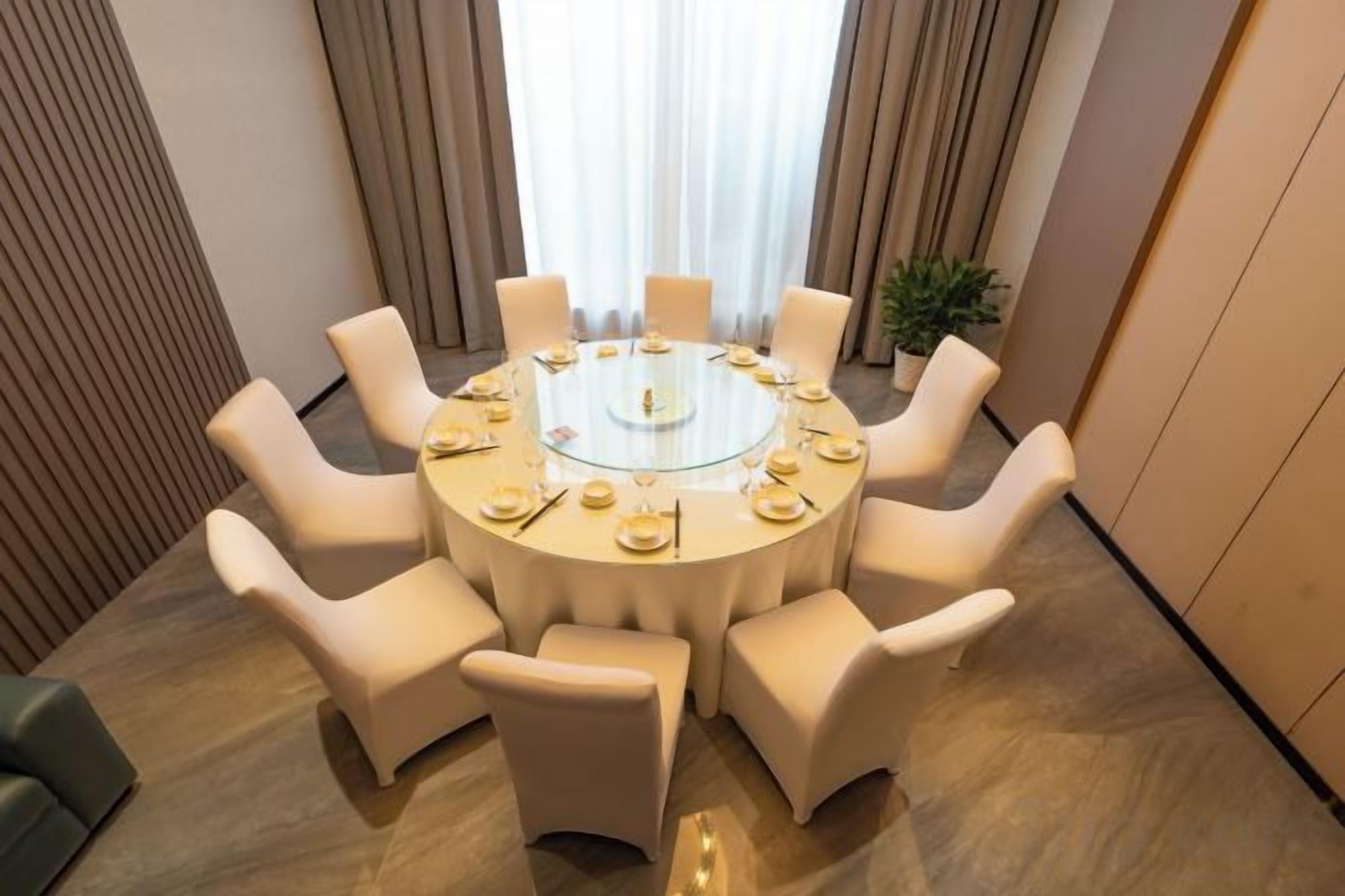 A round table with eight chairs, a glass top, and a central decorative item.