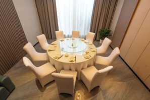 A round table with eight chairs, a glass top, and a central decorative item. - Cotton Rose Hotel (Cili)