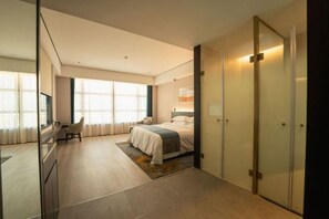 Una habitación de hotel moderna con una cama grande, un escritorio, una silla y un armario.