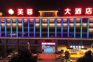 A hotel with a red sign, multiple floors, and a parking lot. - Cotton Rose Hotel (Cili)