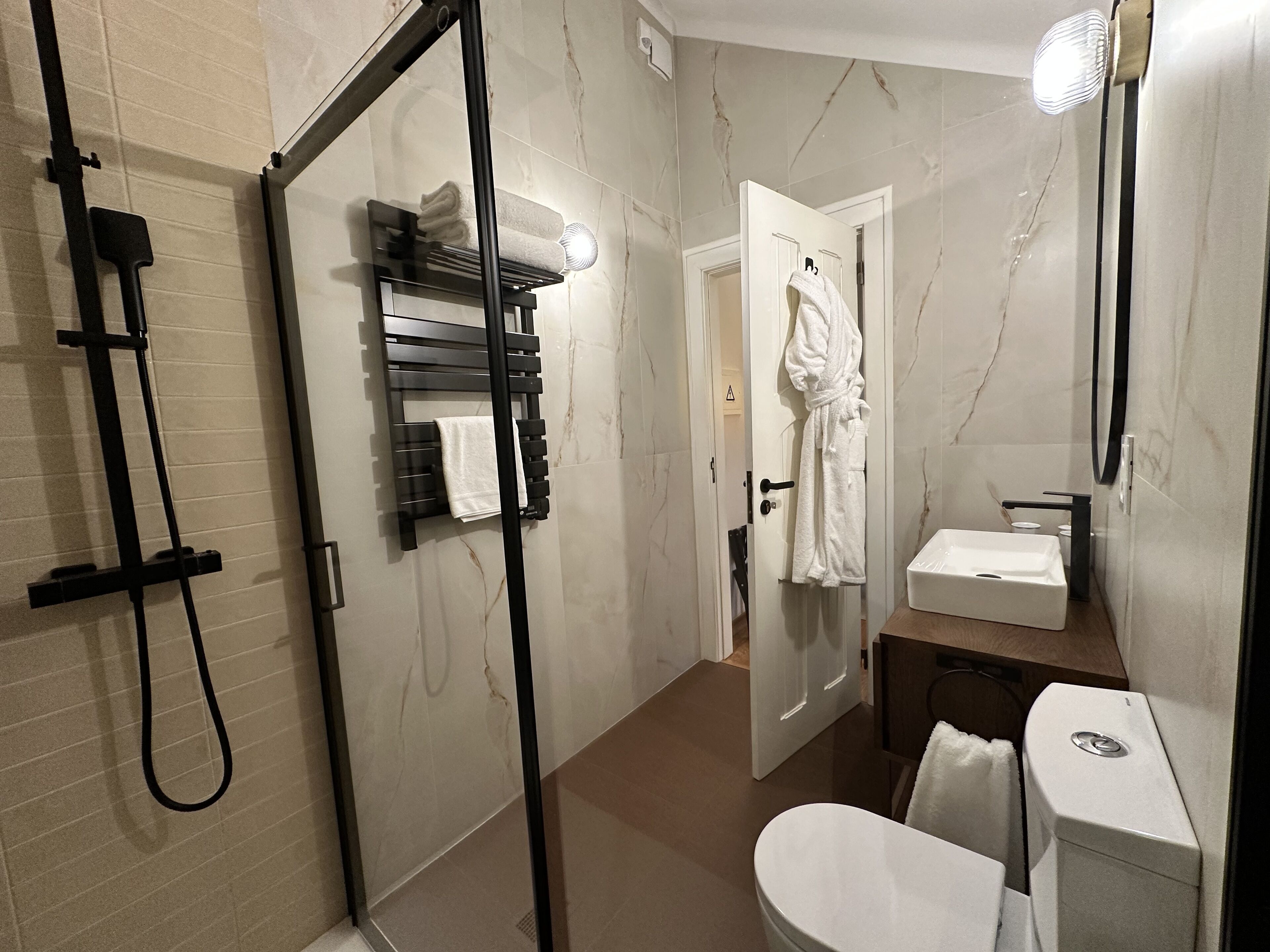 Une salle de bain moderne avec une douche à parois de verre, un porte-serviettes, des toilettes et un lavabo.