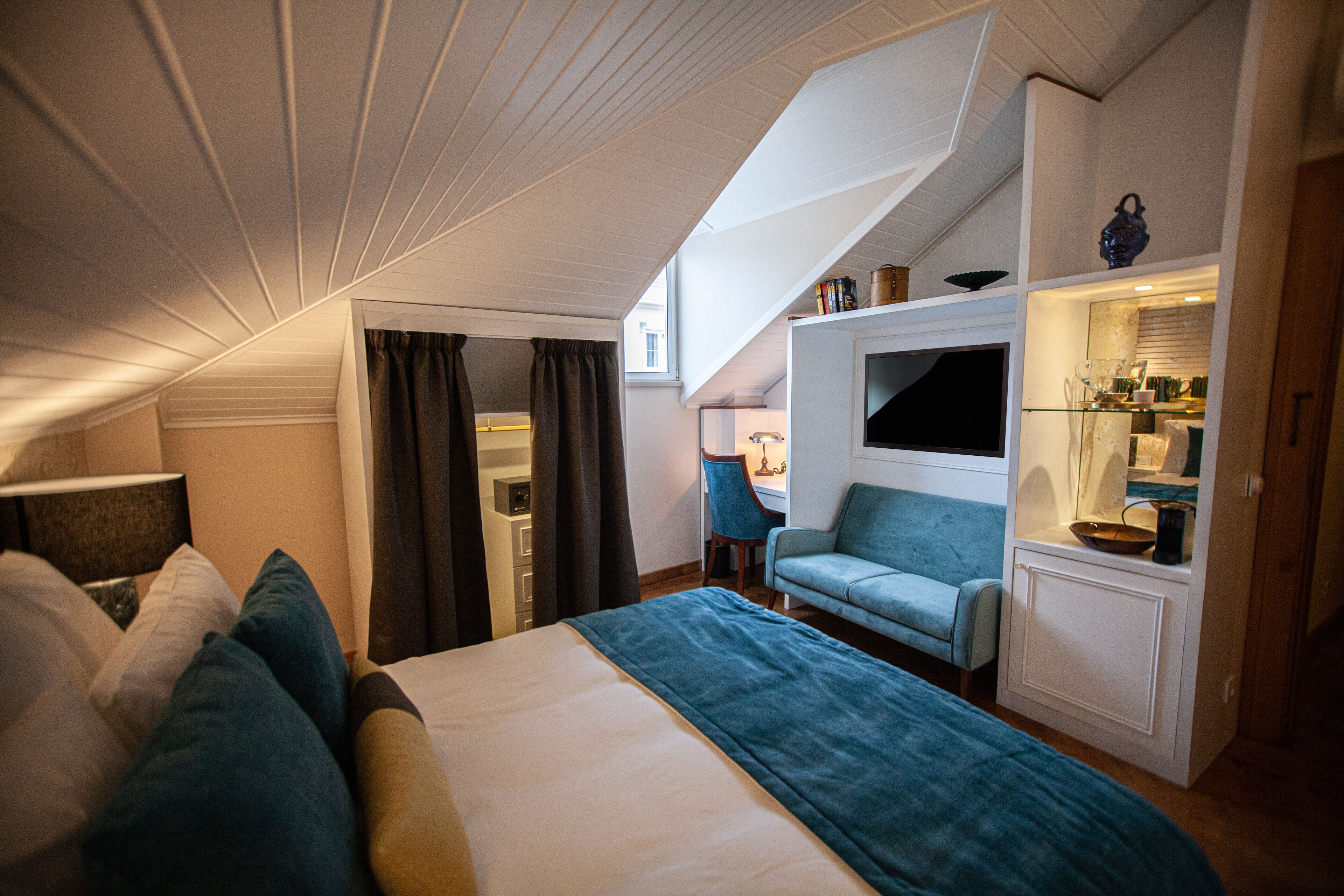 Een compacte, goed verlichte kamer met een bed, een zithoek en een kitchenette.