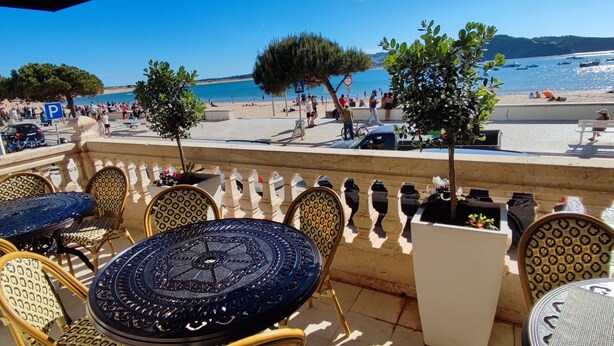 Terraza con mobiliario exterior, con vistas a una playa y al mar.
