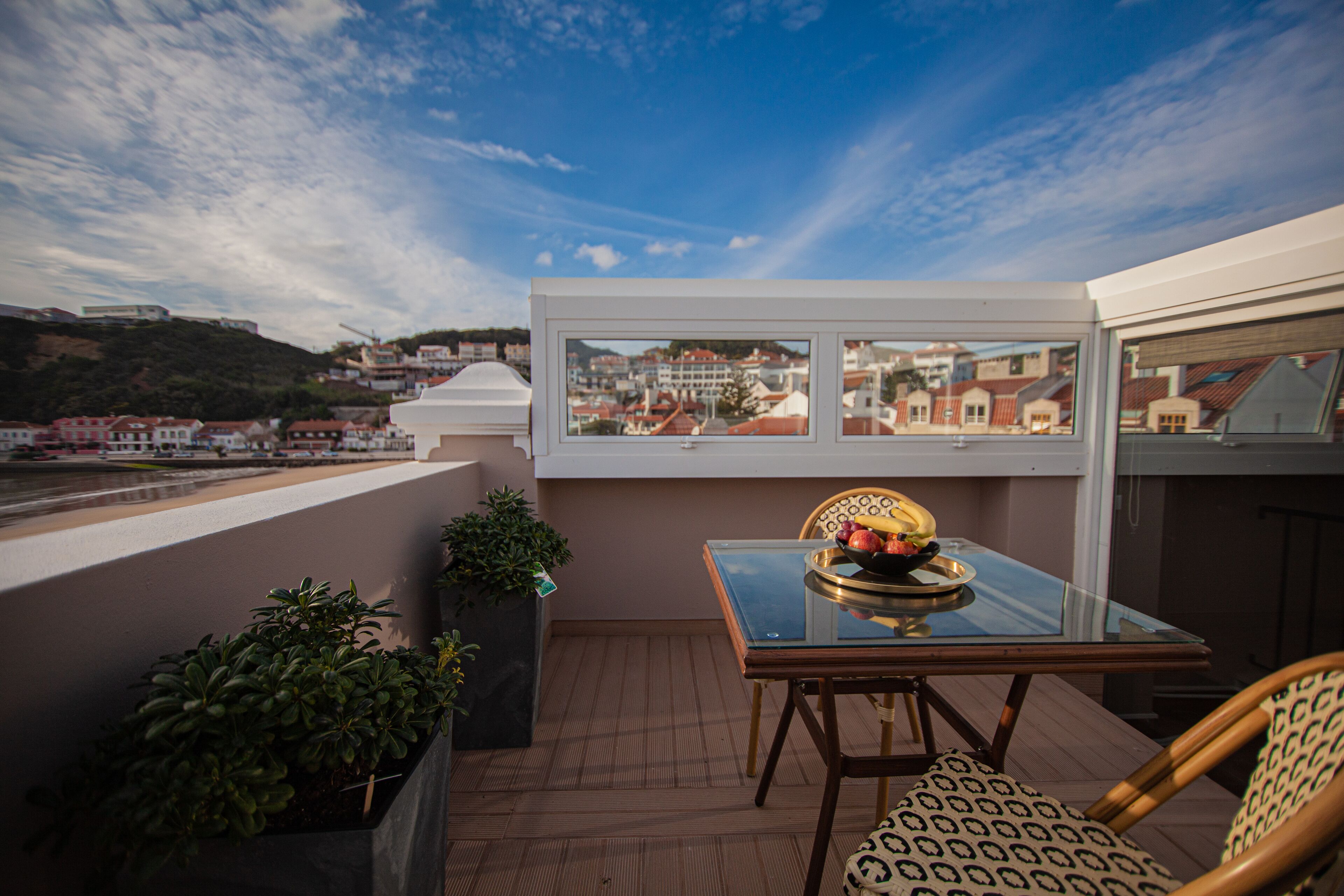 Un balcone con un tavolino in vetro, una sedia e vista su una città.