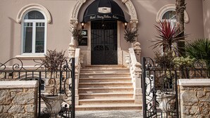 Entrada de hotel con un arco de puerta negro, un letrero sobre la puerta y una escalera que conduce a la entrada.