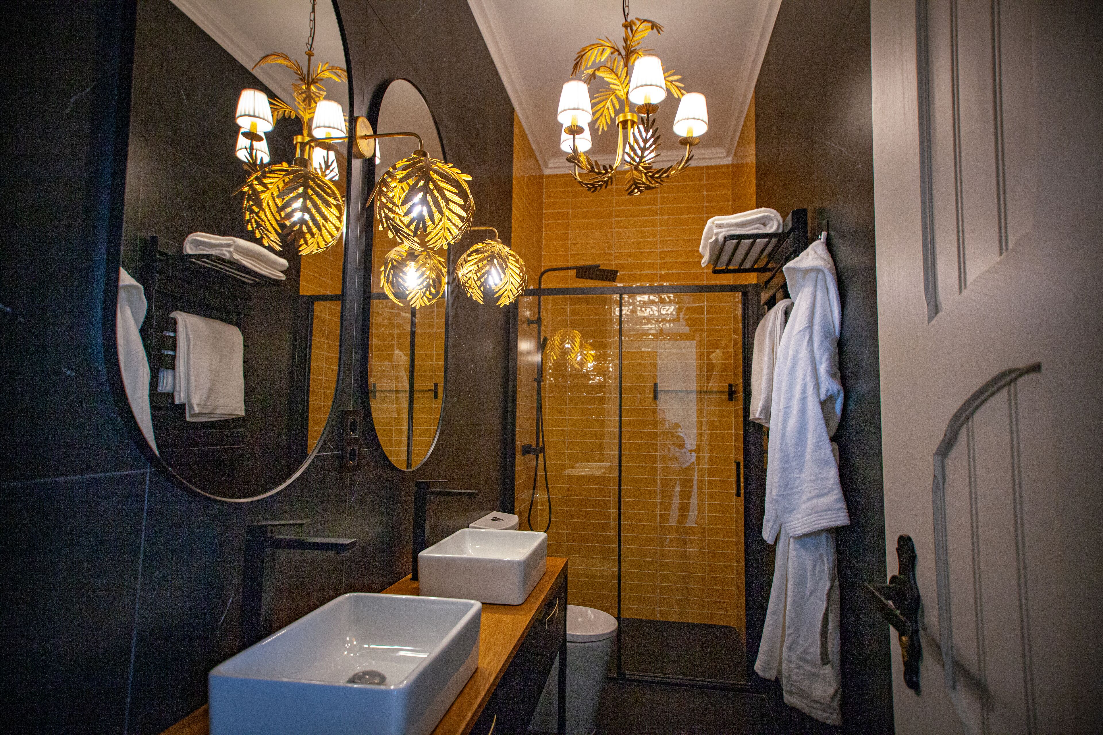 Ein modernes Badezimmer mit einem großen Spiegel, zwei Waschbecken, einer Dusche und einem Handtuchhalter.