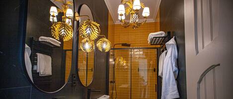 A modern bathroom with a large mirror, two sinks, a shower, and a towel rack.