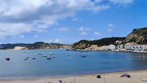 Un pueblo costero con barcos en el agua, una playa de arena y edificios a lo largo de la costa.