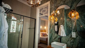 Um banheiro moderno com chuveiro de vidro, parede de mármore e um espelho grande com iluminação decorativa.