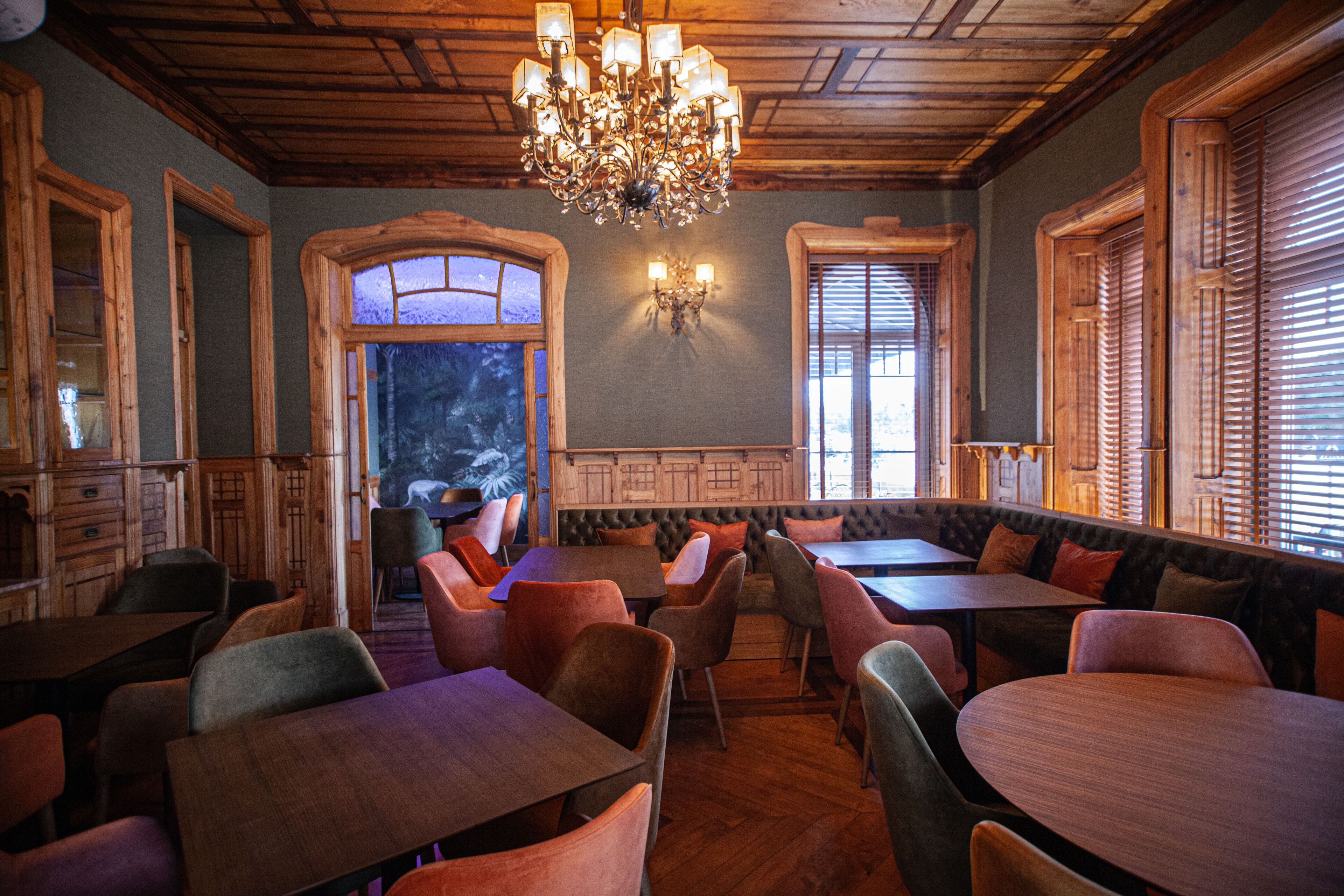 Un restaurant avec des meubles en bois, un lustre et de grandes fenêtres.