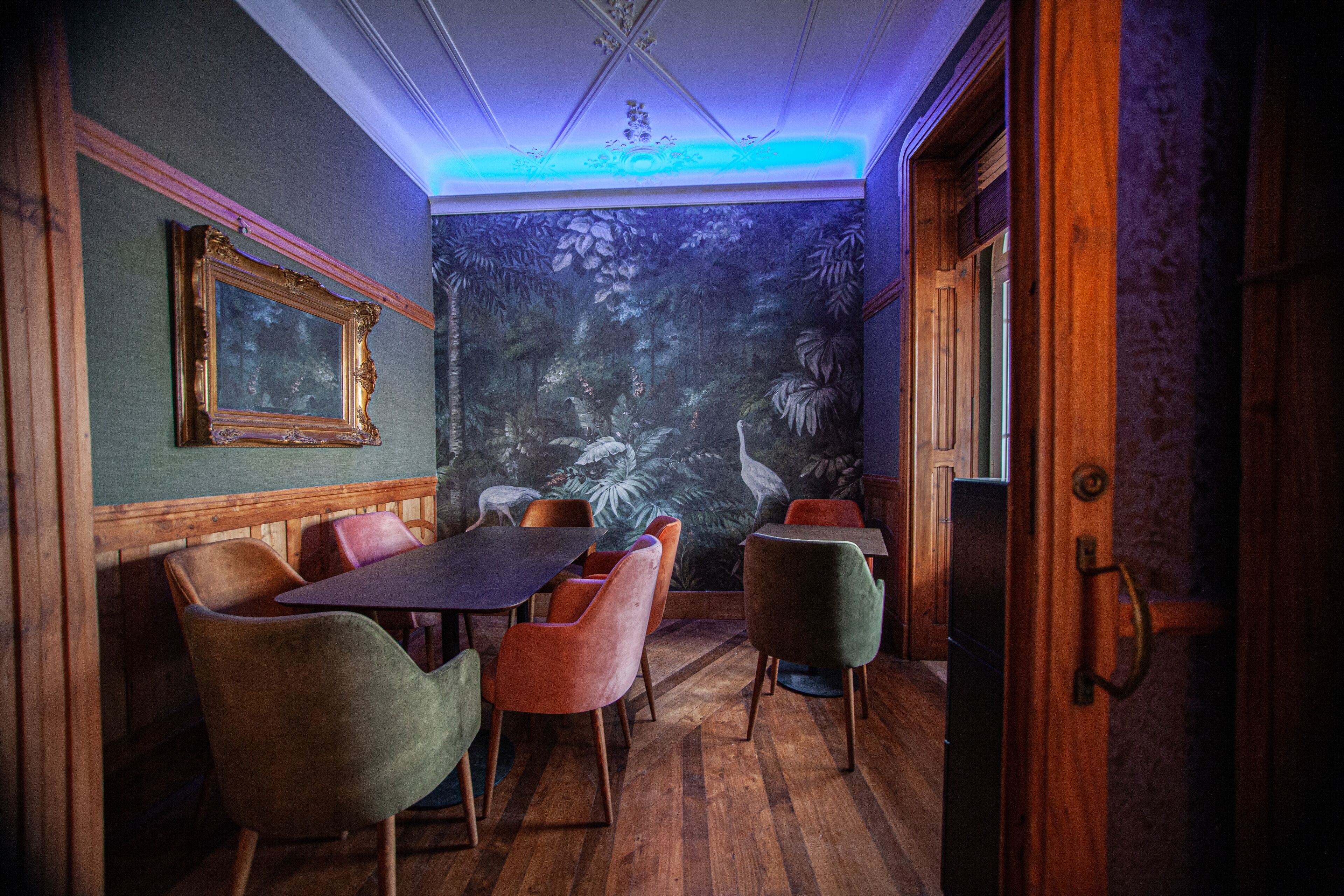 A dining area with wooden furniture and a mural of a forest scene on the wall.