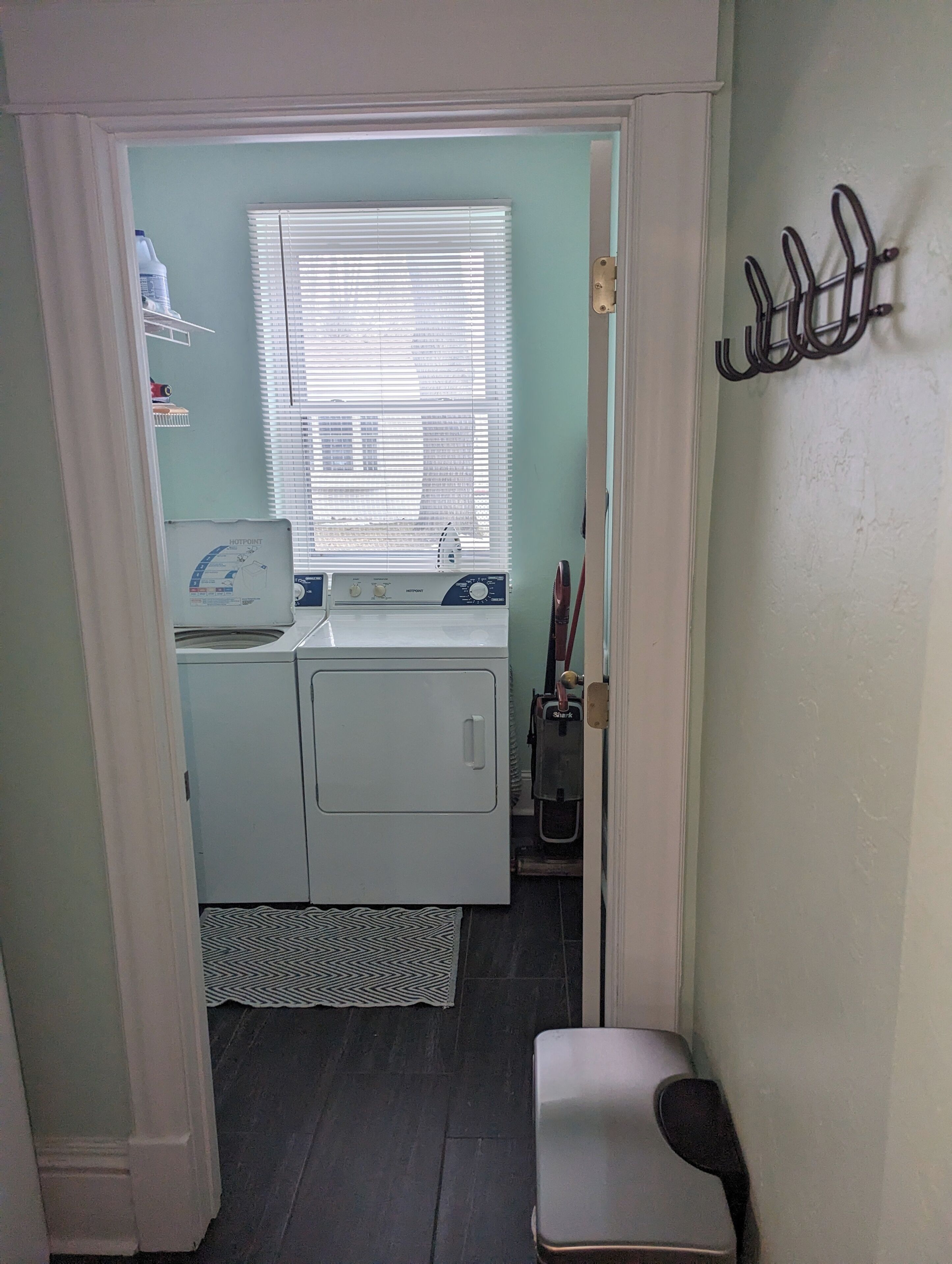 Une buanderie équipée d’un lave-linge, d’un sèche-linge et d’une planche à repasser.