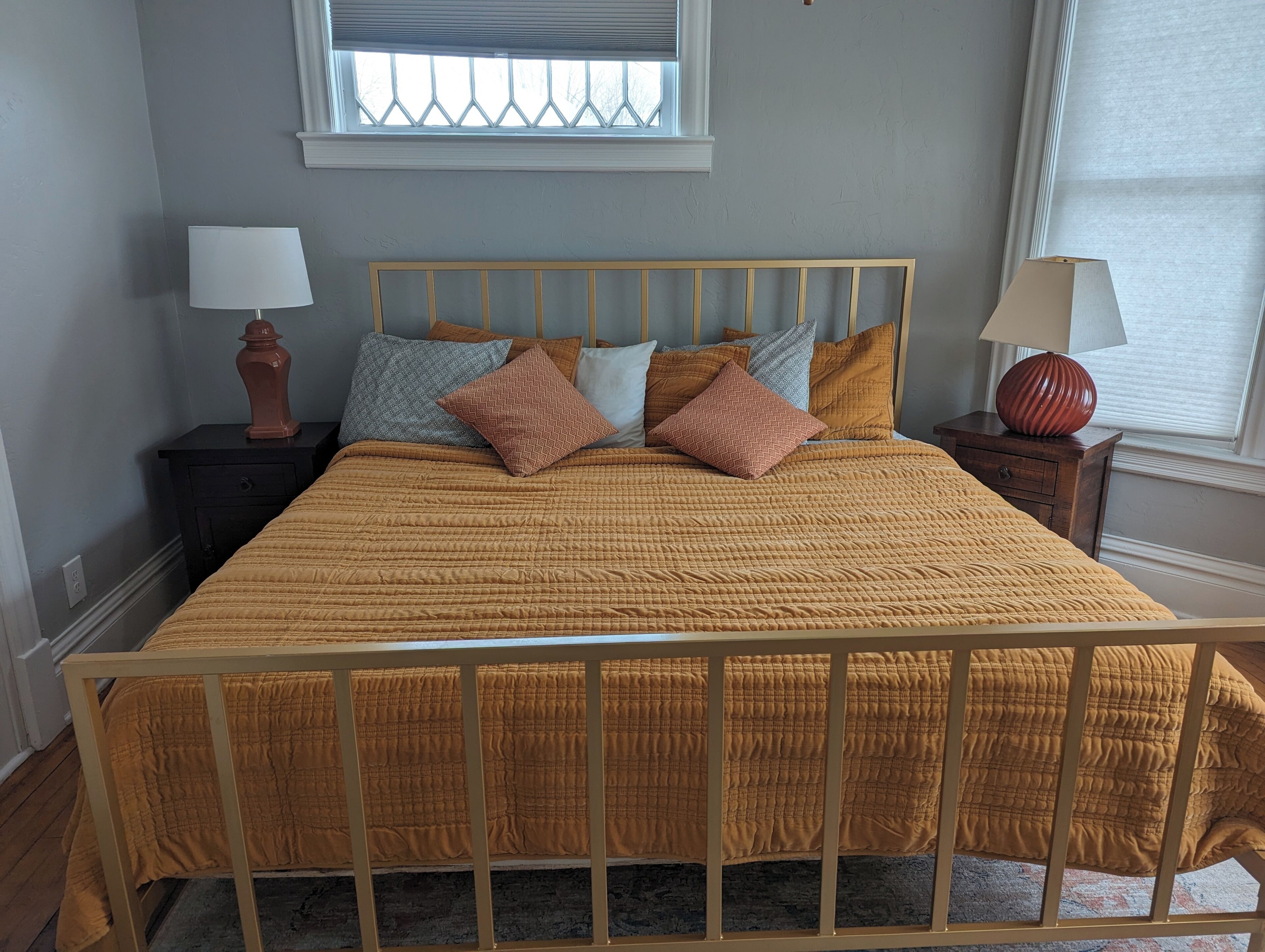 Una cama con estructura de madera, cabecera y colcha acolchada.