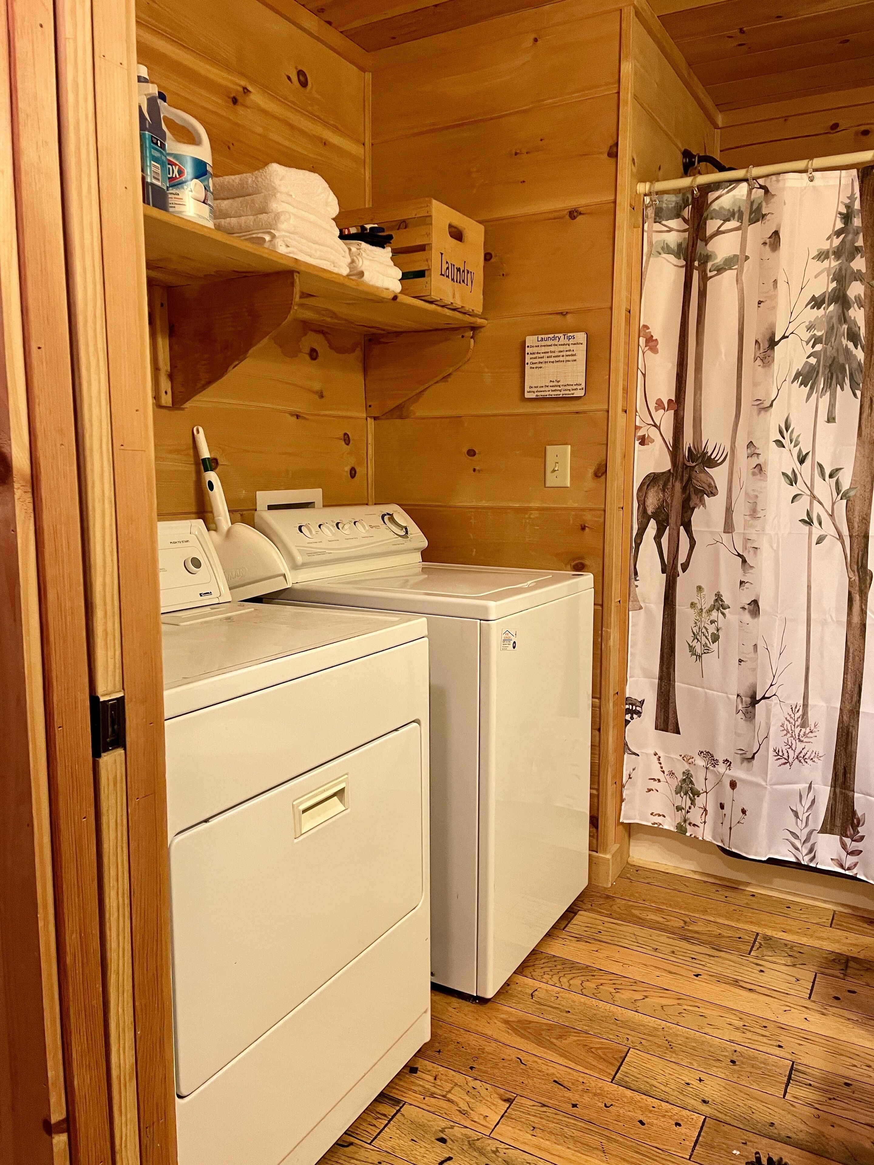 A laundry room with a washing machine, dryer, and shelves with laundry supplies.