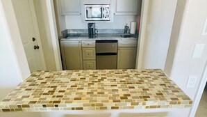 A compact kitchen with a microwave, coffee maker, and dishwasher. - Enjoy GULF FRONT sunsets in newly renovated private studio in private home. (Palm Harbor)