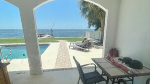 A covered patio with a pool, a table, and chairs, overlooking a beach and the ocean. - Enjoy GULF FRONT sunsets in newly renovated private studio in private home. (Palm Harbor)