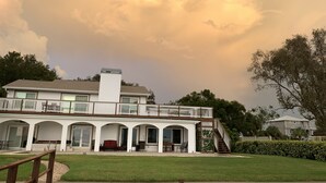 A two-story house with a covered patio, a fenced yard, and a large tree. - Enjoy GULF FRONT sunsets in newly renovated private studio in private home. (Palm Harbor)