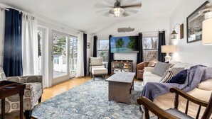 A spacious living room with a large window, a ceiling fan, a wooden coffee table, and a sofa.