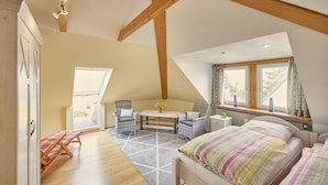 Une chambre à coucher avec un lit, deux chaises, une table et une fenêtre avec des rideaux.