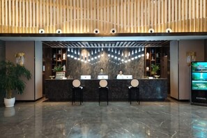 A reception desk with three chairs, a potted plant, and a TV screen. - Suiyang Wolong Lake Resort (Suiyang)